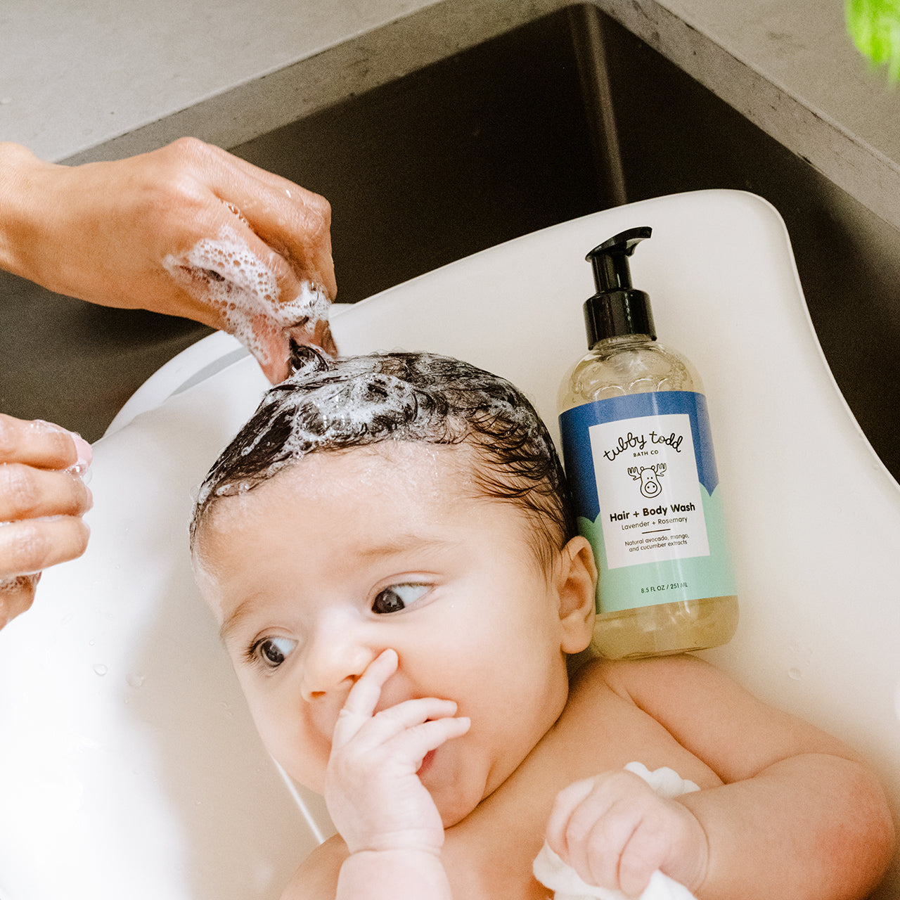 Mom washing her baby girl's hair with the Lavender Rosemary Hair Body Wash on the sink.
